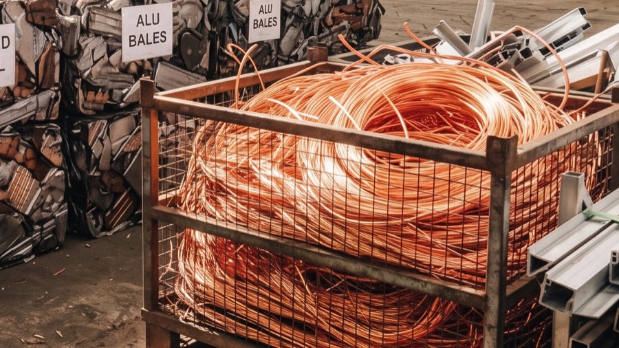 Cage of copper wire scrap beside baled aluminium and profiles