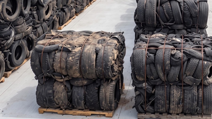 Baled truck and bus tyres strapped on pallets in the yard